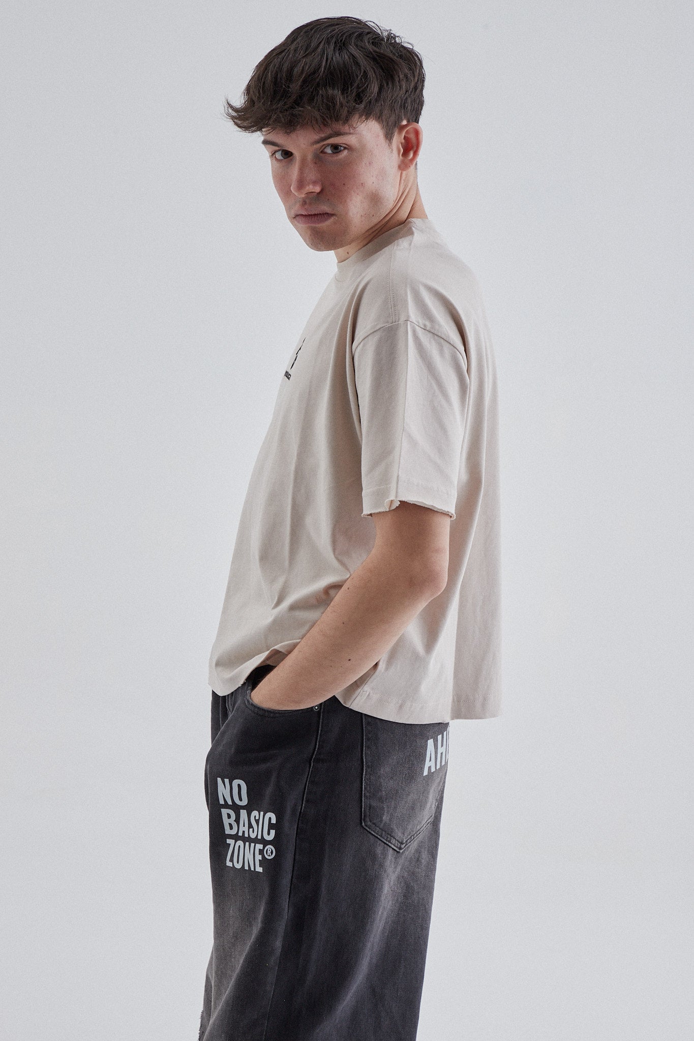 Camiseta beige y negra con logo de No Basic Zone, estilo casual, visible en la imagen.